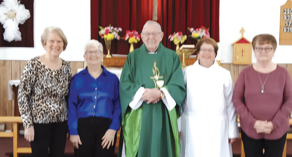 a group of four ladies and one male priest standign at the front of a church